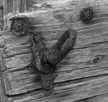 This rusted tie-down is on the side of a well-worn farm wagon. 