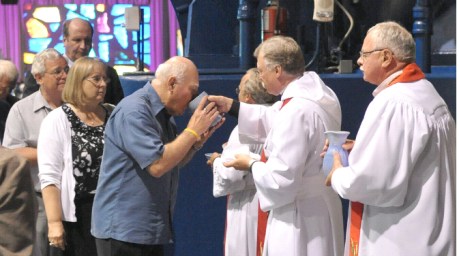 Pastor David Schultz (right) serves Holy Communion at opening service of LCMS Convention